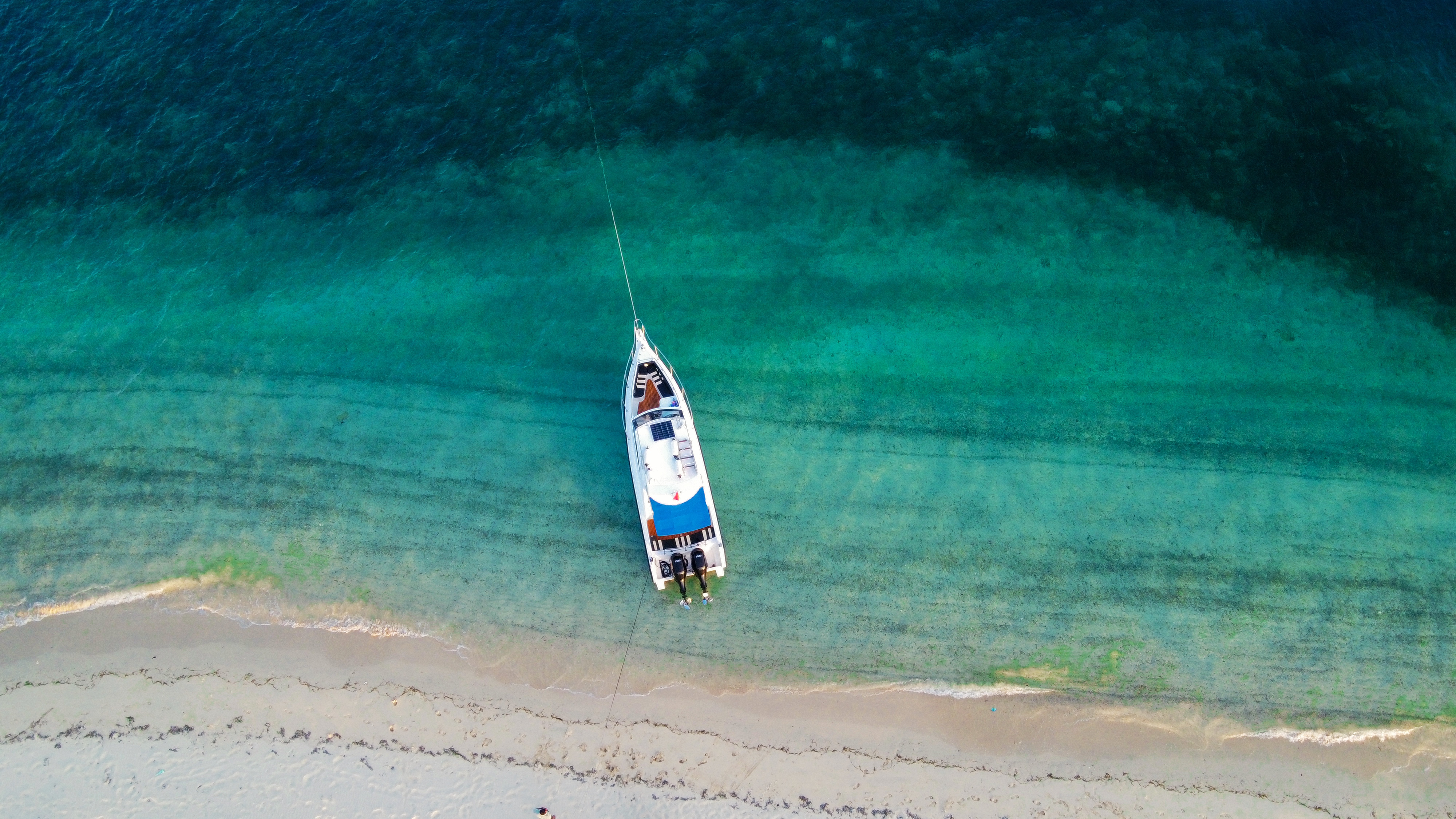 Modern speedboat racing across emerald green waters with lush tropical mountains in the distance